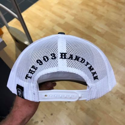 A white mesh back baseball cap held by a hand, embroidered with 