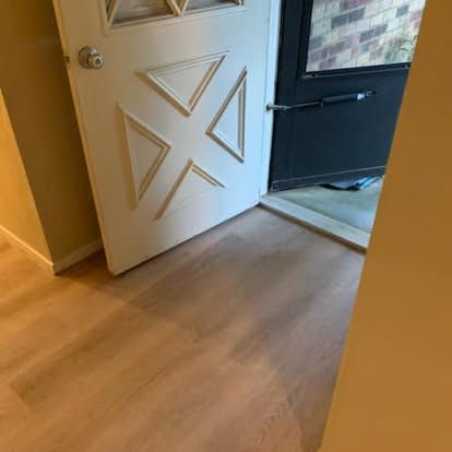 A white interior door with a geometric design and a silver knob, slightly ajar, revealing a black screen door.