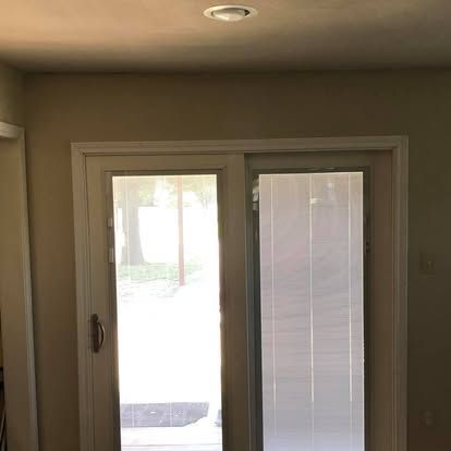 A white sliding glass door framed in a beige wall, with a ceiling light fixture visible above.