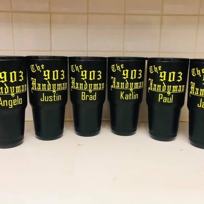 Six black tumblers lined up, each labeled with yellow text 