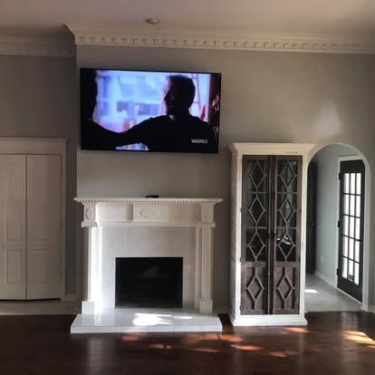 A wall featuring a fireplace and a mounted television screen, flanked by a closed white door and a tall display cabinet.