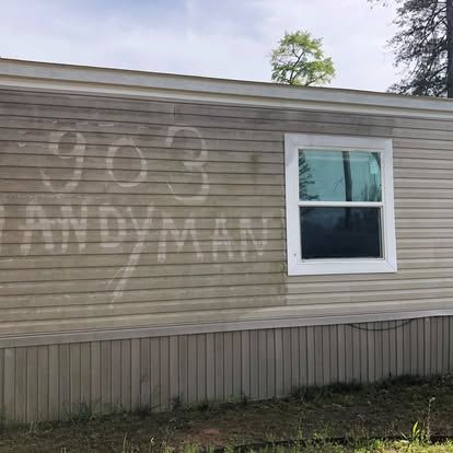 A mobile home with a dirty, light-colored vinyl exterior featuring the faded, cleaner text 
