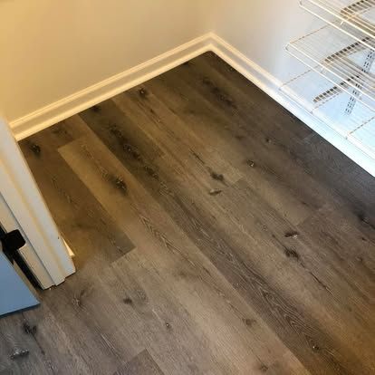 Light brown wood-look vinyl plank flooring inside a closet with white baseboards and white wire shelving.