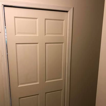A white, six-panel interior door set in a doorframe against a neutral-colored wall.