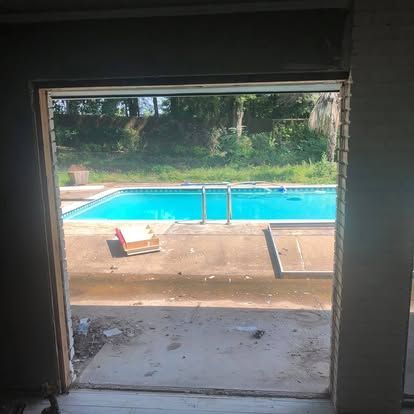 A view from a doorway looking out onto a backyard with a bright blue swimming pool and a surrounding patio.