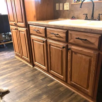Wooden cabinetry with a sink, black faucet, and patterned countertop in a kitchen.
