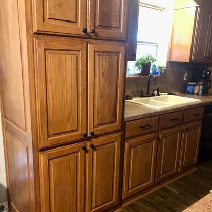 A kitchen interior featuring light oak wood cabinets, a white double-basin sink, and a window above the counter.