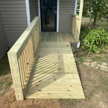 A wooden ramp with a handrail leading up to the entrance of a house.
