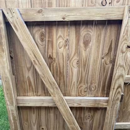Close-up of a wooden fence gate constructed with vertical panels and diagonal cross-bracing.