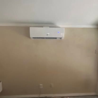 A white wall-mounted air conditioner unit installed on a beige interior wall.