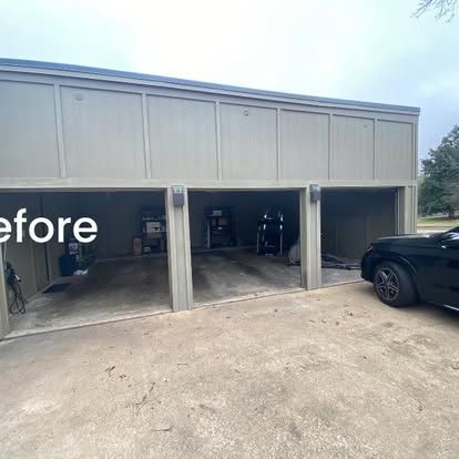 A tan-colored, three-bay garage with open doors and a black car parked to the right on a concrete driveway.