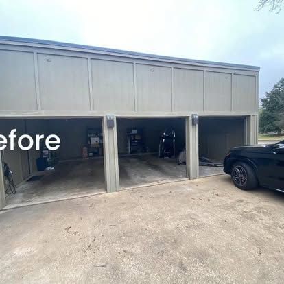 A three-bay, open-front garage with beige wood paneling and a concrete driveway, with a black car parked to the right.