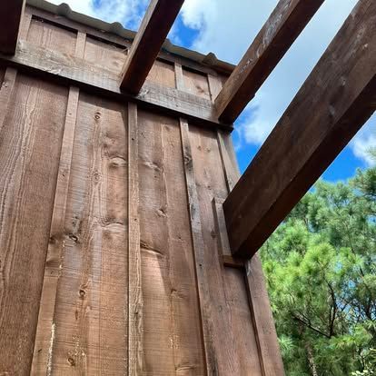 Low-angle shot of wooden beams extending from a rustic, vertical-planked wooden wall against a partially cloudy blue sky.