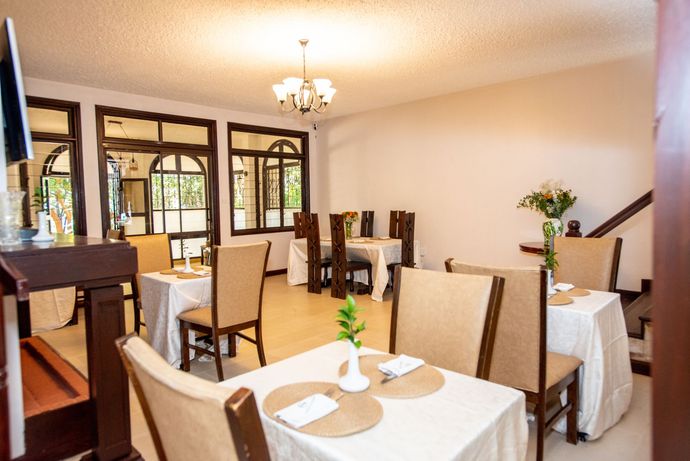 Cozy Stead Bright dining room with neatly set tables, beige chairs, and a chandelier under warm lighting