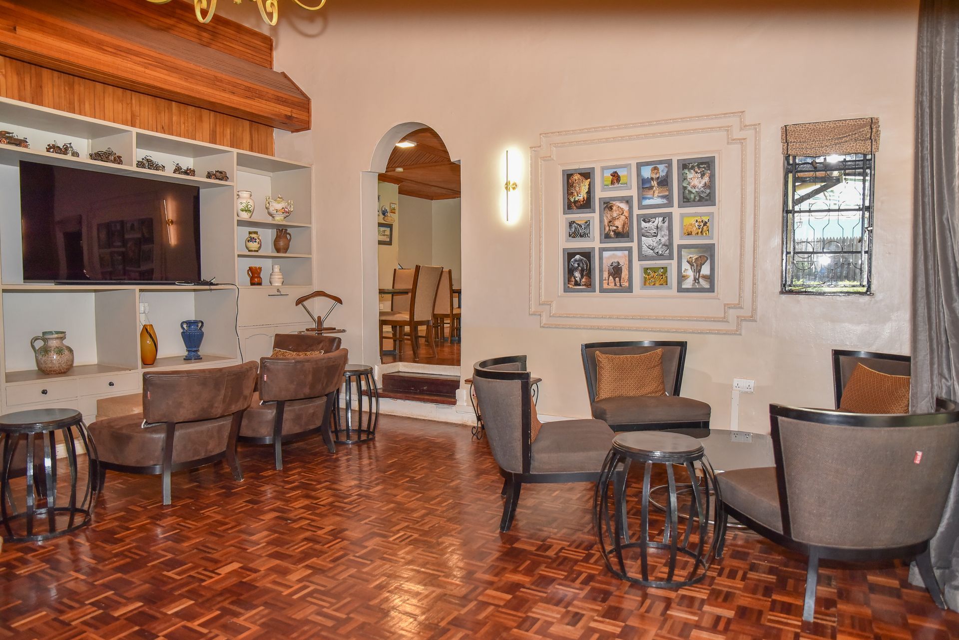 A lit living room with floors and seating areas, including armchairs and sofas, and a framed collection of artwork.