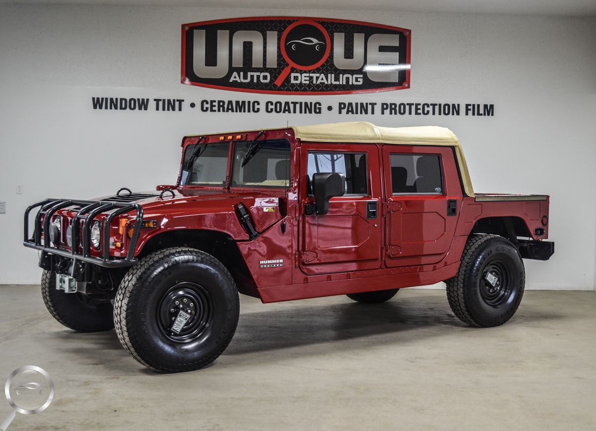 Red lifted pickup truck in a showroom, with black wheels and rugged off-road tires.