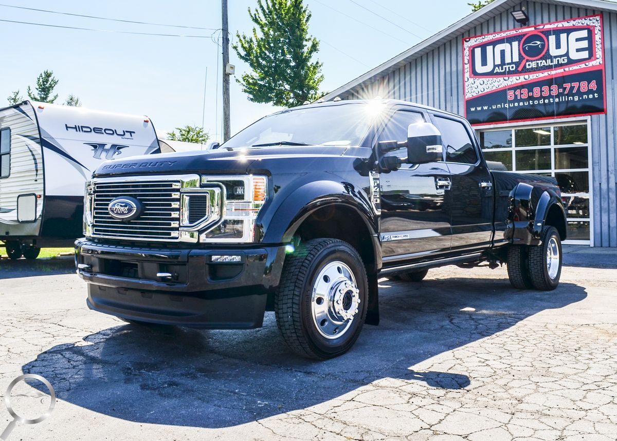 Black Ford pickup truck parked outside a dealership with a UNIQUE sign.