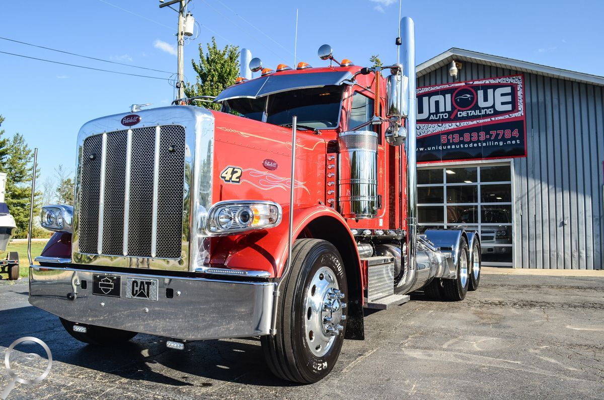 Red semi truck parked outside an auto shop on a sunny day