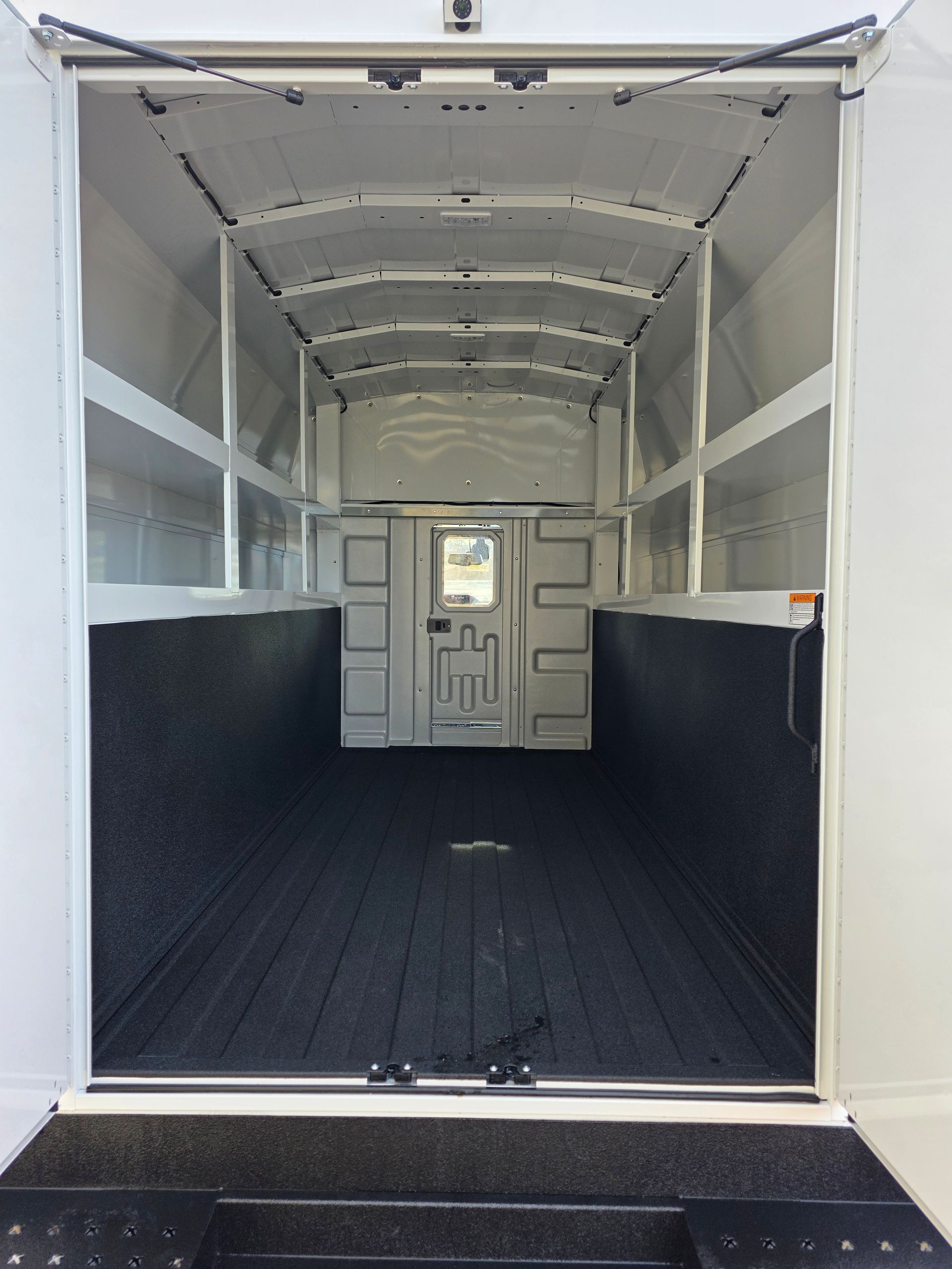 Empty white cargo truck interior with black floor and open rear door