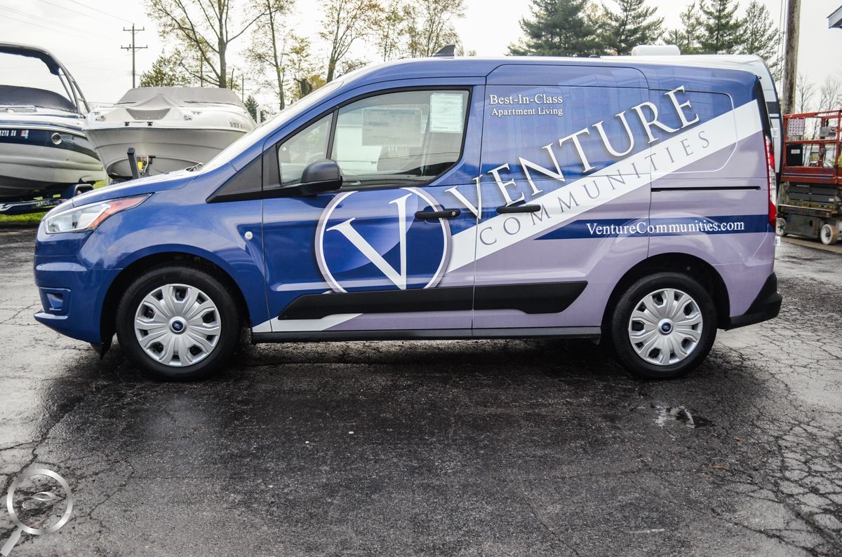 Blue cargo van with white nature-themed branding parked on a wet lot