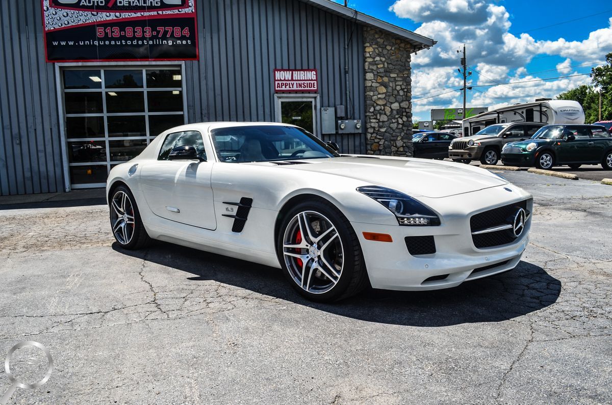 White sports car parked outside an auto shop on a sunny day