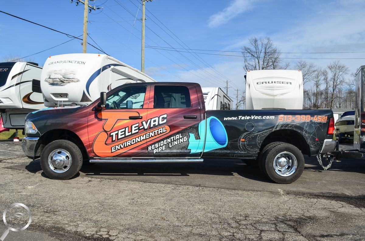 Orange race truck with TeleVac branding parked outdoors on a sunny lot