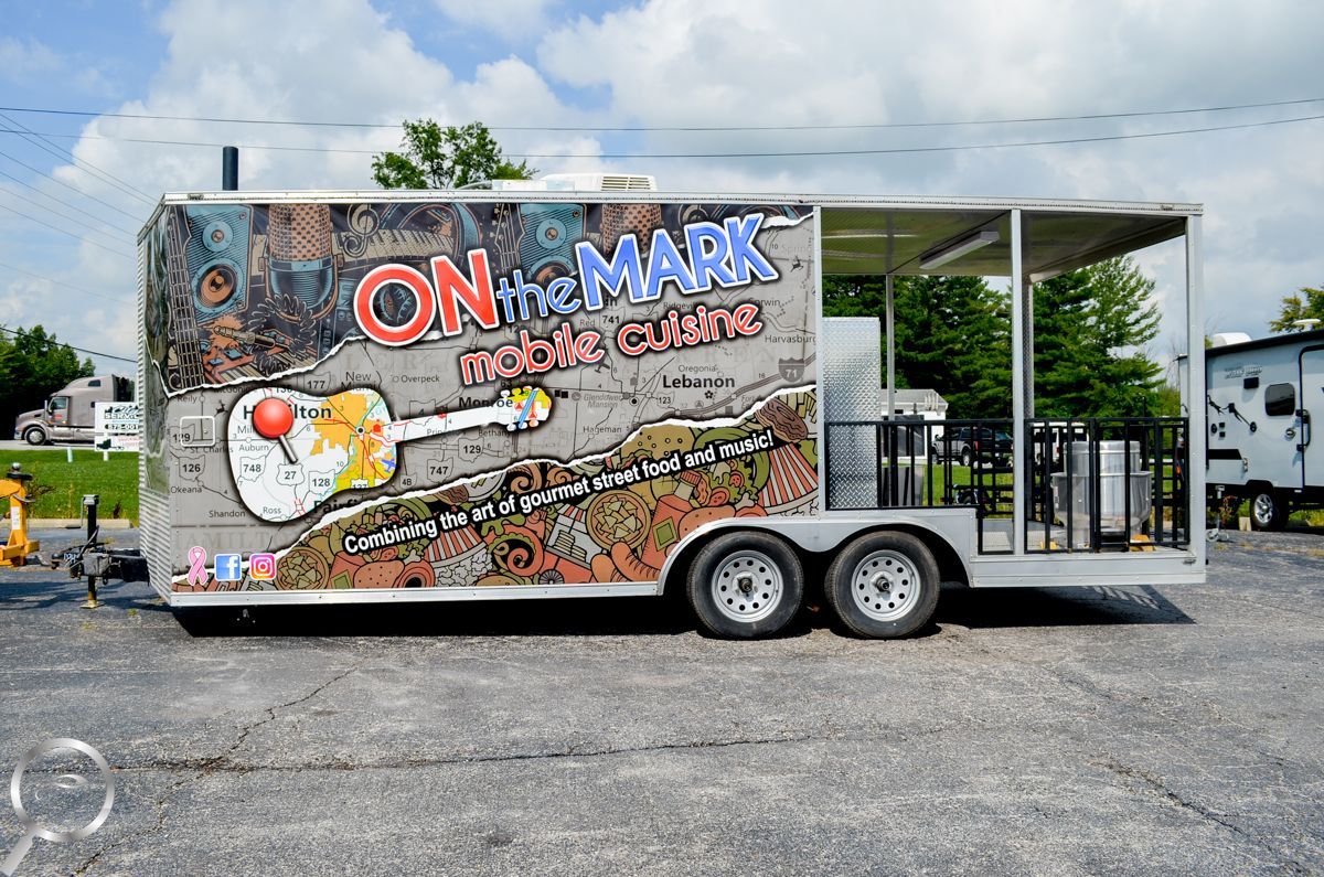 Graffiti-covered food trailer with two wheels parked on pavement under a canopy