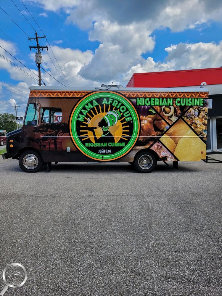 Food truck with “Nigerian Cuisine” signage and green circular logo parked on a street under a blue sky