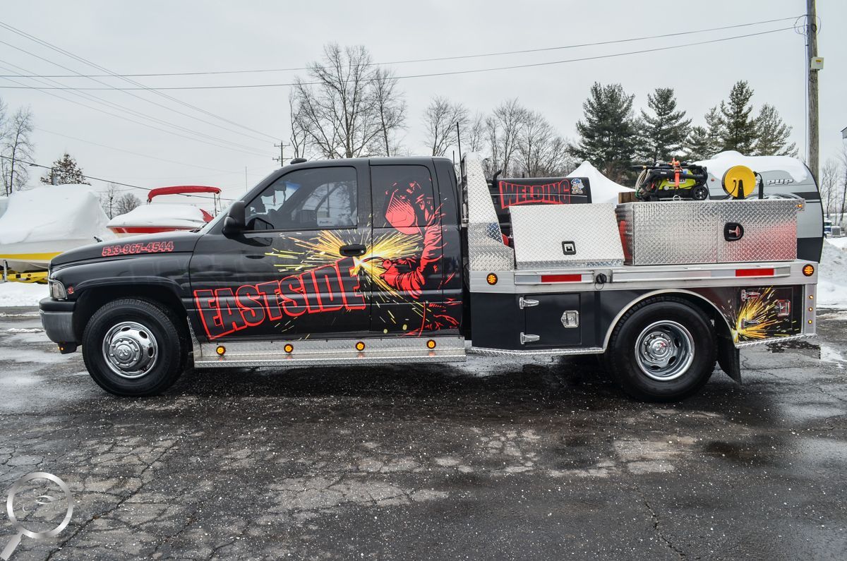 Black and white tow truck with red flame graphics parked on a snowy roadside