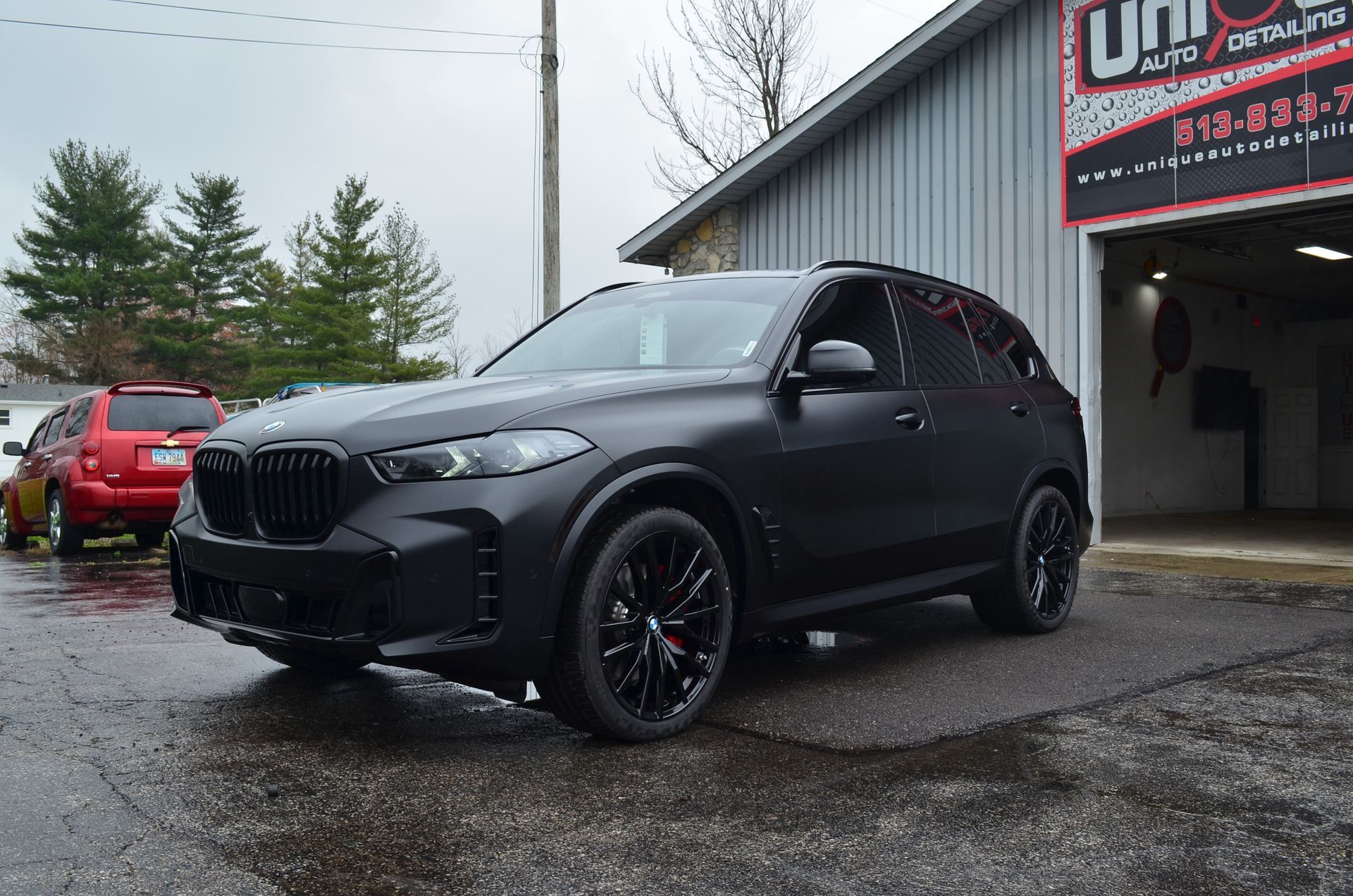 Black BMW SUV parked outside a building on a wet day