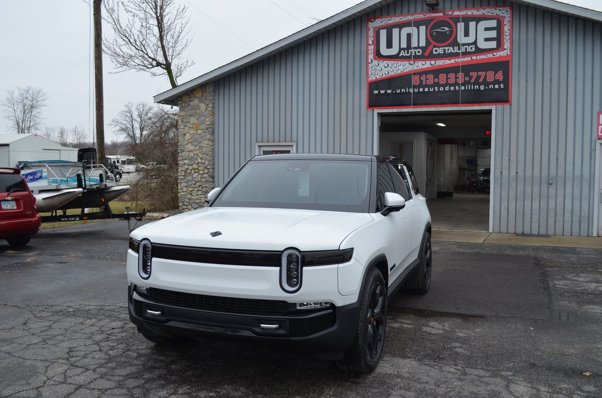 White SUV parked outside a garage with a UNIQUE sign above the entrance