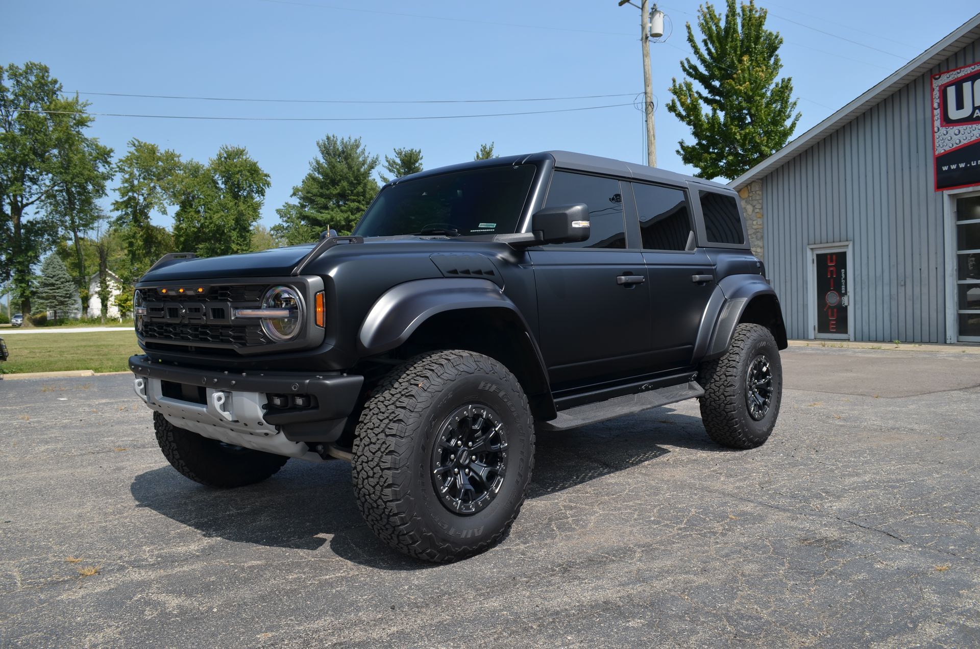 Black lifted Ford Bronco parked outside a shop on a sunny day
