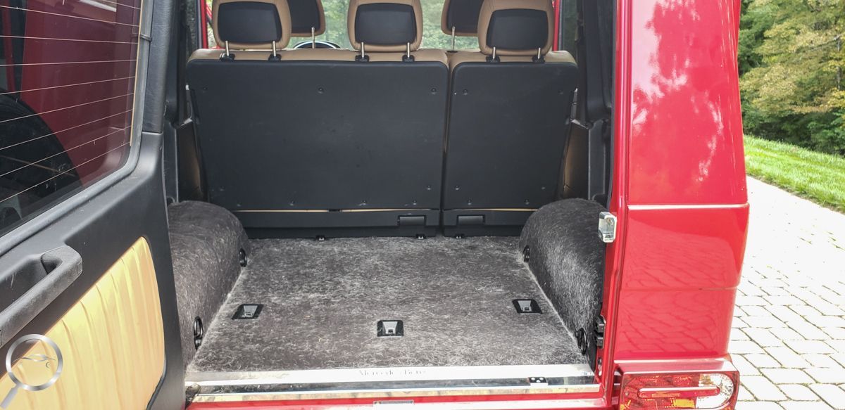 Open cargo area of a red van with gray carpeted floor and folded black seats.