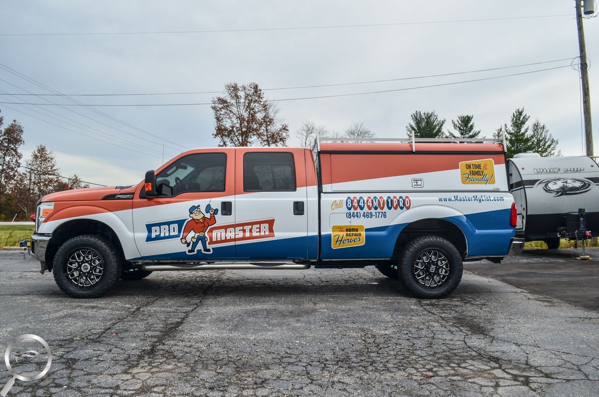 Colorful pickup truck with a mural-style wrap parked on a cracked lot under an overcast sky