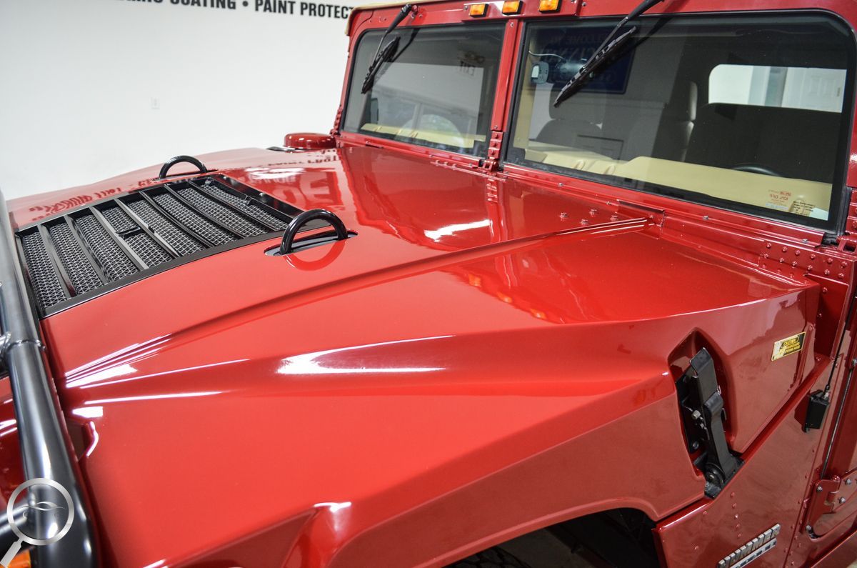 Red classic car hood and windshield in a showroom, with a glossy red finish and black wiper blades