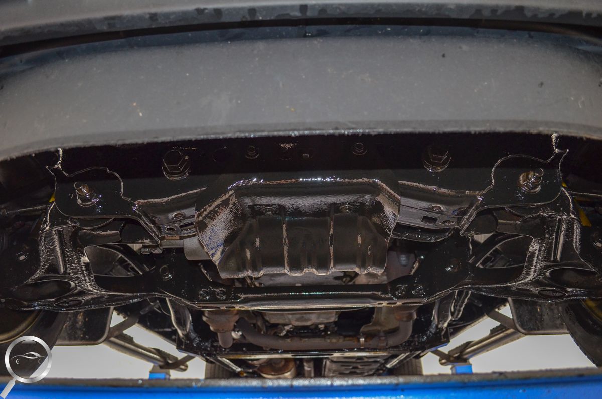 Undercarriage of a car on a lift, showing the exhaust and suspension components