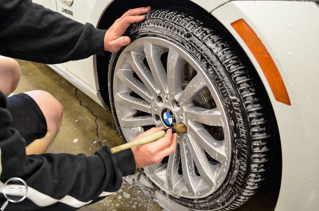 Hands tightening a BMW wheel on a white car in a snowy setting