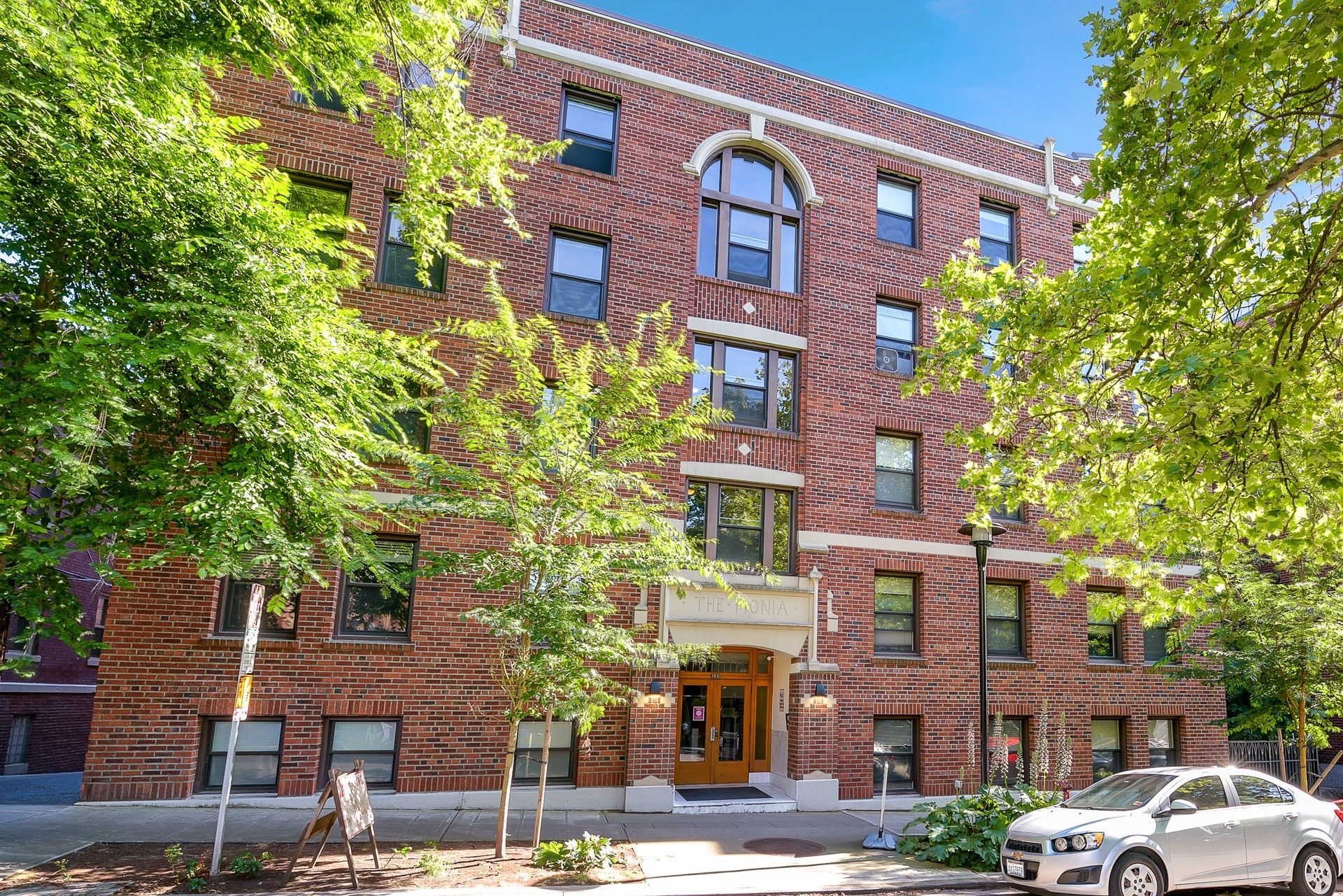Photo of the building, showing five stories and a variety of trees outside