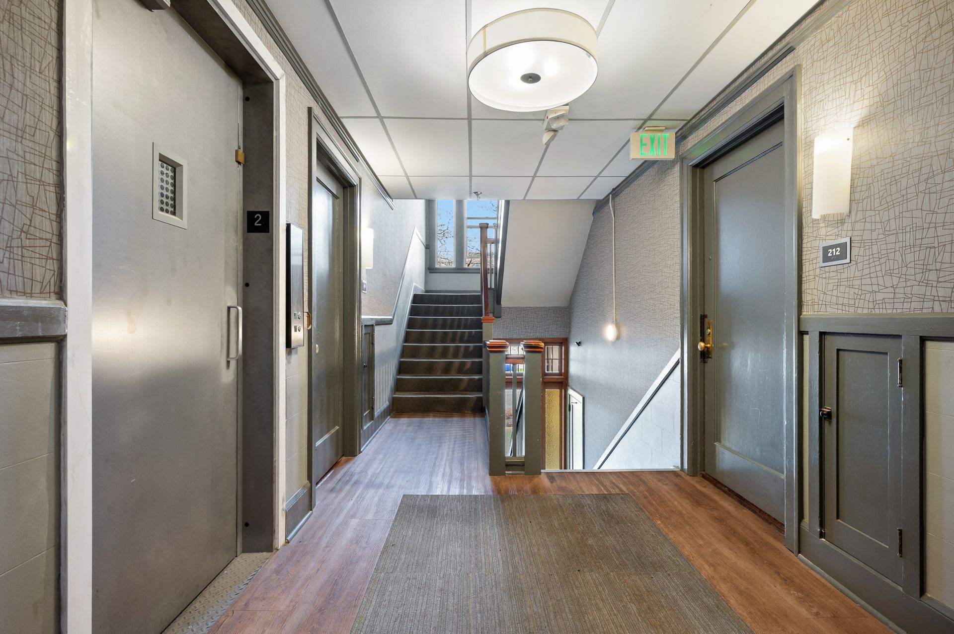Photo of a stairway landing and the entrance to an apartment, as well as an elevator
