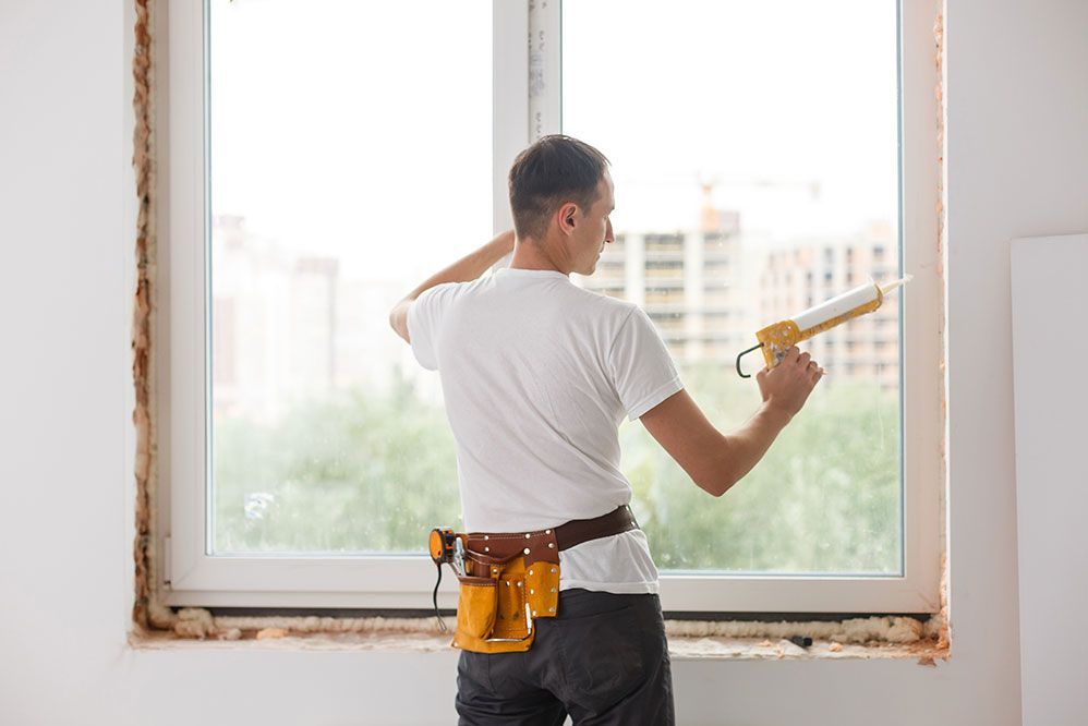 Un homme installe une fenêtre dans une maison.