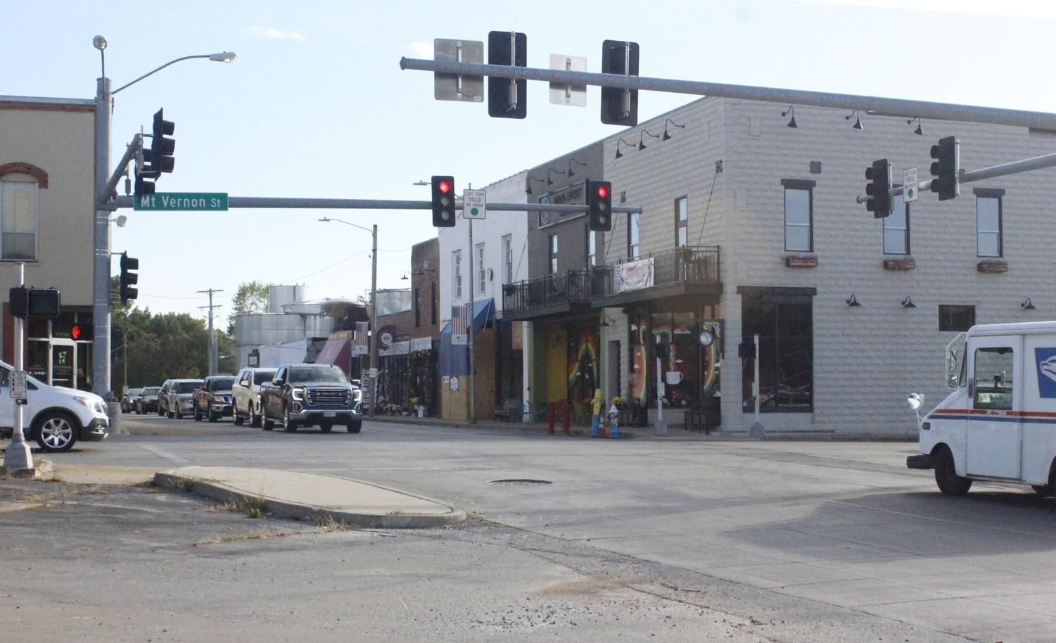 Street intersection with buildings, traffic, and a mail truck. Red traffic lights.