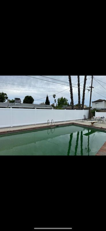 A large swimming pool with a white fence around it.