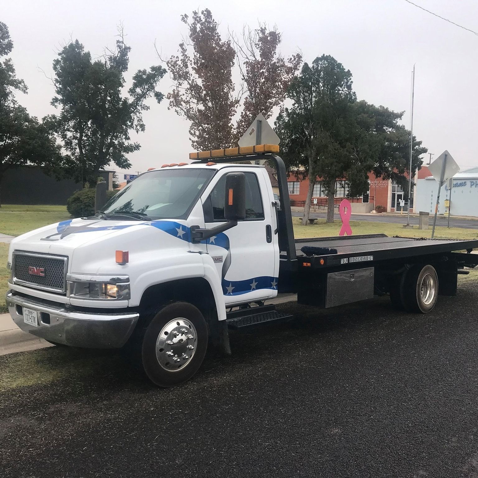 White GMC tow truck parked on asphalt street.