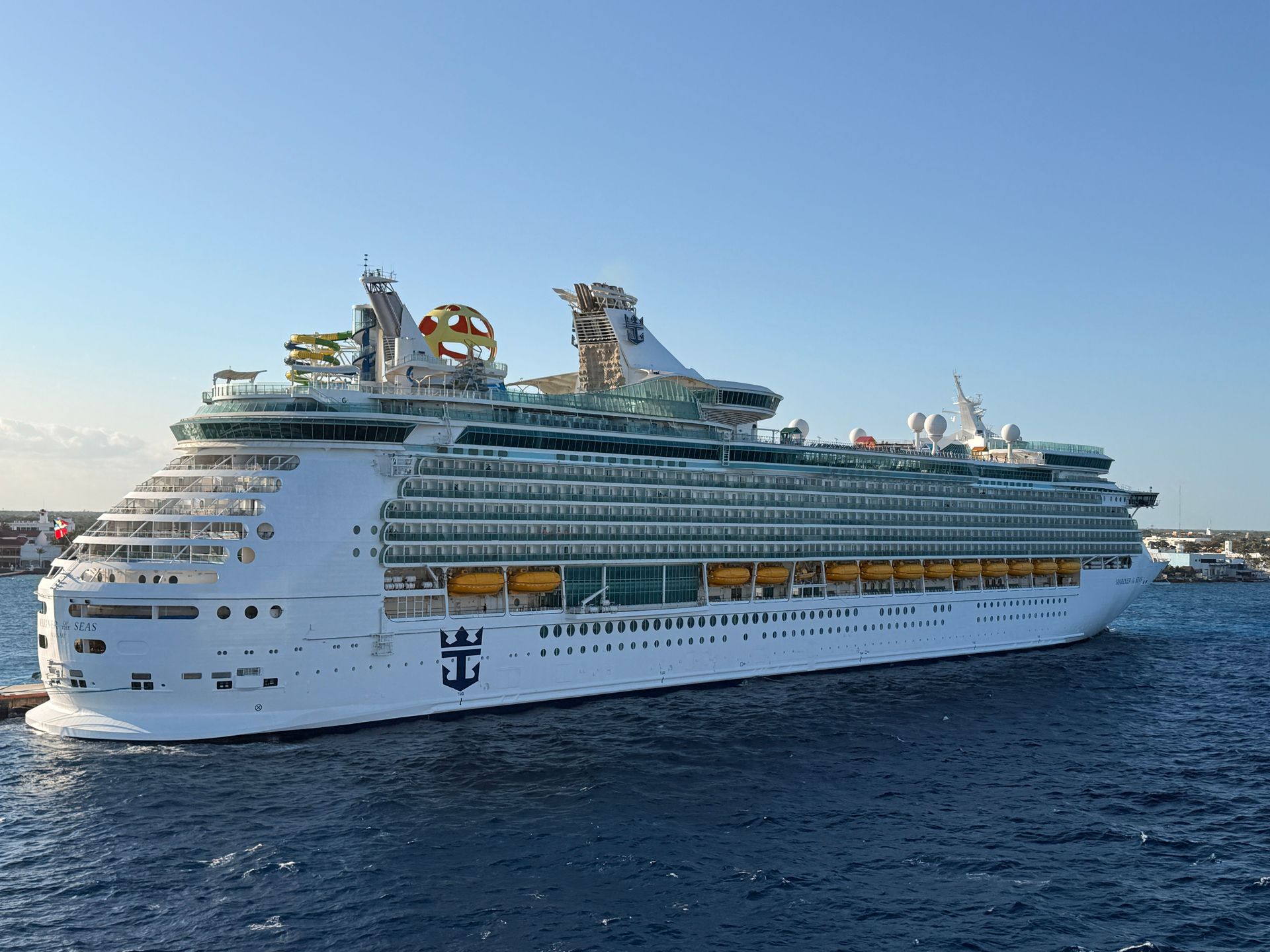 Large white cruise ship sailing on deep blue water under a clear sky