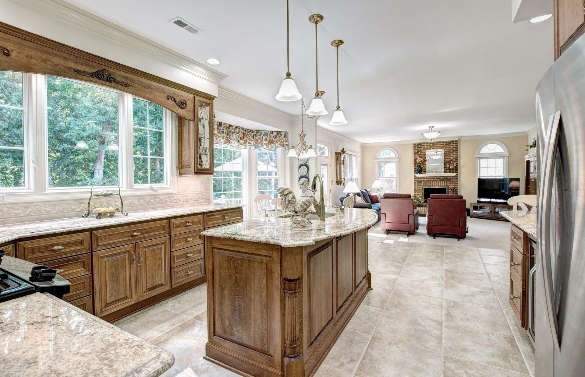 Large bright kitchen with wood cabinets, granite island, and red chairs in an open dining area