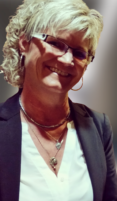 Frau lächelt, trägt Brille, Blazer und Halsketten.