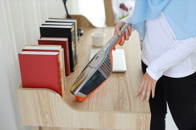 a woman using a hand vacuum in cleaning
