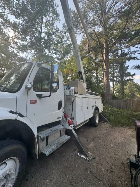 A white truck with a crane attached to it is parked in a driveway.