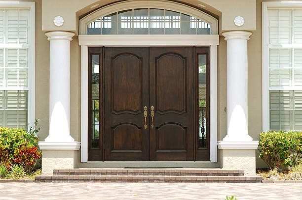 the front door of a house with a wooden door and white columns .