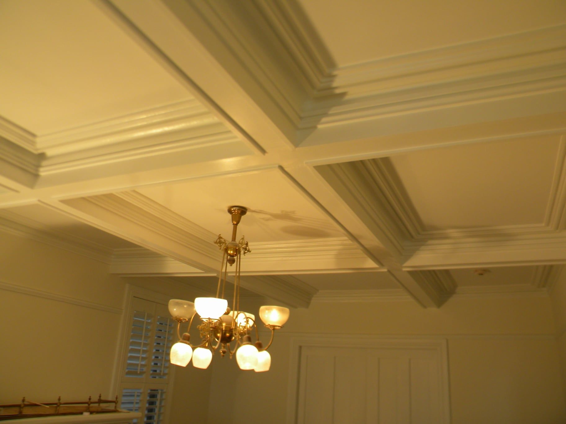 a chandelier is hanging from the wood tray ceiling of a room